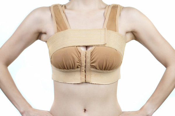 Woman posing in support bra after breast reduction surgery