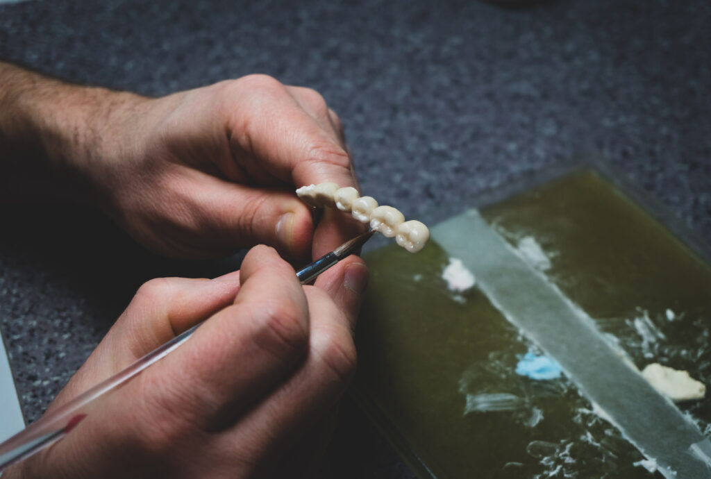 dental technician makes dental crowns. close-up. - مميزات وأنواع التيجان السنية